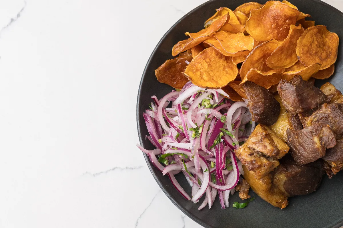 Chicharrón de chancho — fried pork belly with sweet potato chips and sarza criolla